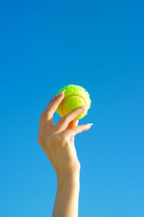 Close-up of a Person Holding a Tennis Ball on the Background of Blue Sky · Free Stock Photo