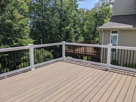 Trex Enhance composite decking in Toasted Sand with white vinyl Washington-style railings and black aluminum balusters. Brown Composite Deck With White Railing, White Trex Deck, Wood Deck With Composite Railing, Trex Toasted Sand Deck, Tan Deck With White Railing, Trex Enhance Toasted Sand, Trex Coastal Bluff Vs Toasted Sand, Trex Deck Toasted Sand, Biscayne Trex Deck