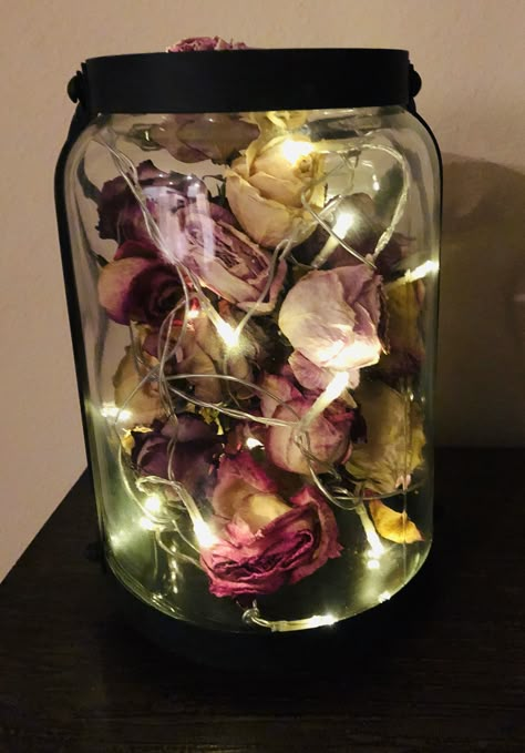 Wondering what to do with your dried roses? Take a string of mini lights, a decorative glass jar and arrange all together for a beautiful decoration that is also meaningful 💕 Dried Flower Petals In A Jar, Dried Roses Crafts, Dried Roses Room Decor, Dry Roses Decoration, Dried Roses Wedding Decor, Diy With Dried Roses, Rose Petals Decoration Ideas, Things To Do With Flowers From Boyfriend, Dried Rose Decoration