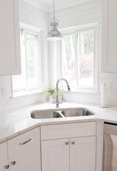 Double basin stainless steel corner sink in white kitchen. Double Sink Corner Kitchen, Kitchen Sink With White Cabinets, Corner Double Sink Kitchen, Kitchen Ideas With Corner Sink, Corner Kitchen Sink Design Ideas, Caddy Corner Sink Kitchen, Kitchen With Corner Sink And Island, Small Sink For Kitchen, Basin Design Kitchen