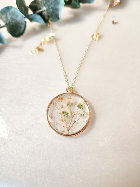 These beautiful flowers are frozen and time and will never lose their bloom or fade! Each Babies Breath necklace will contain dried pressed babies breath flowers, along with dazzling, pretty gold or silver leaf flakes which sparkle in the sunlight. This handmade necklace is a beautiful piece of pressed flower jewelry and they will look stunning on whoever wears these unique gift for her. This pretty Pressed Wildflower Necklace is made with REAL dried and pressed flowers! The wildflowers will mak Pressed Flower Resin Jewelry, Babies Breath Flowers, Wildflower Necklace, Dried Flower Necklace, Handmade Gold Necklace, Aesthetic Gifts, Easy Crafts To Sell, Real Flower Necklace, Cottagecore Jewelry