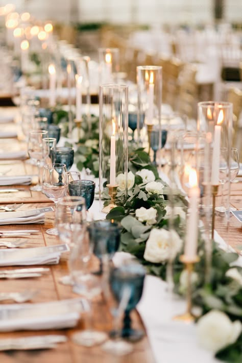 Greenery garland with pops of white flowers for long farm table centerpiece. Taper candles to accent. Captured by Gabby for Emily Wren Photography https://emilywrenweddings.com/ Candle Chimney Wedding, Farm Table Garland Wedding, White Long Table Centerpiece, Farm Table Wedding Decor Candles, Taper Candles Long Table Wedding, Centerpieces Wedding Farm Table, Candle Long Table Centerpiece, Wedding Table With Taper Candles, White Flowers Candles Wedding