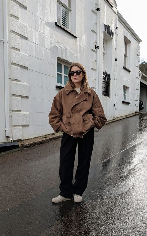 A woman stands in front of a white house. She wears black sunglasses, a short brown jacket, black trousers and white canvas shoes. Short Coat Outfit, Short Jacket Outfit, Casual Weekend Outfit, Studio Nicholson, Casual Outfit Inspiration, Spring Jacket, Canvas Jacket, Jacket Outfit, Casual Weekend