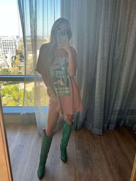 girl taking mirror selfie wearing knee high green cowboy boots and oversized graphic tee Urban Cowboy Boots Outfit, Pointed Cowboy Boots Outfit, Cowboy Boots Outfit Colorful, Graphic Tee Cowboy Boots Outfit, Colored Cowboy Boots Outfit, Green Western Boots Outfit, Boho Outfit With Cowboy Boots, Graphic Tee And Cowboy Boots Outfit, Cowboy Boots Airport Outfit