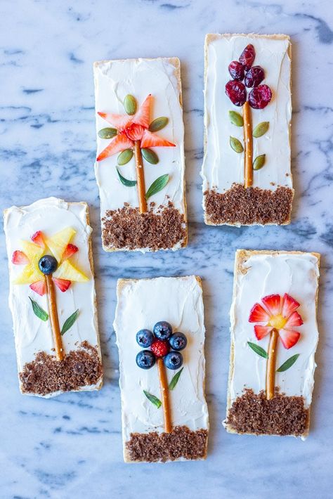 These Flower Garden Graham Crackers are so fun to make, beautiful to look at and delicious to eat! Both you and your kids will have a blast making them! You can go off the designs we have here or get super creative and design your own flowers! The possibilities are endless! #grahamcrackers #foodart #kidfriendly #fruit #flowers Kid Snacks, Food Art For Kids, Fruit Flowers, Kid Food, Toddler Snacks, Snacks Für Party, Kids Food, Fun Kids Food, Food Crafts