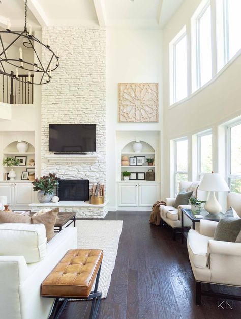 White Living Room Design with Statement Two Story Painted Stone Fireplace White High Ceiling Living Room, White Living Room Fireplace Ideas, White Stone Fireplace Living Room, Black Window Living Room, 2 Story Family Room Fireplace, Tall Stone Fireplace Decor, White Tall Fireplace, Fireplace Great Room Ideas, Two Story Great Room Wall Decor Ideas