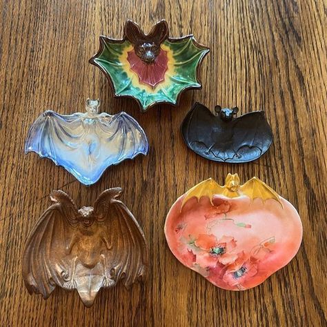 the lantern house on Instagram: "A few pieces from my antique bat collection. These are calling card/pin/ash dishes from the late 19th early 20th c. Clockwise from top: Continental polychrome “majolica", B&H cast iron, Limoges hand-painted/gilded porcelain, French ormolu bronze, and Bavarian lusterware. #ilovebats #favoritecollectionsfriday #antiquehalloween #spookycollections #bats #spookyseason #chauvesouris #halloween #dark #murcielago #fledermaus #vintagebat" Bat Pottery, Bat Ceramic, Clay Bat, Bat Painting, Lantern House, Bat Decor, Bat Design, The Lantern, Calling Card