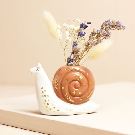 A little vase to display your favourite dried posy  	In a snail shape with sweet golden details all over  	Made of sturdy ceramic in cream and brown shades  	Perfect for gifting to a lover of quirky home accessories     Product Information     This adorable little snail is the perfect way to display your favourite mini posy of dried blooms.     With a cream-coloured body beneath a brown shell, this little snail is adorned with golden spots, stars and leaves to create the sweetest piece of home d Snail Accessory, Animal Vase, Cute Ceramics, Ceramic Snail, Quirky Homeware, Ceramic Bud Vase, Lisa Angel, Personalized Housewarming Gifts, Personalized Anniversary Gifts