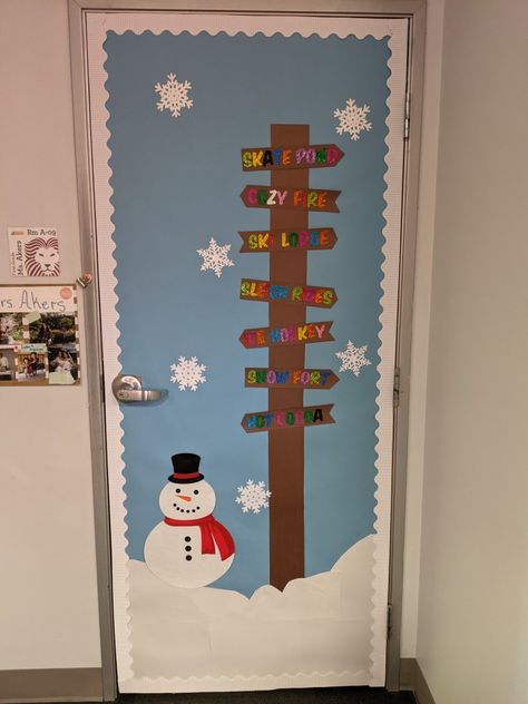 Winter classroom door decoration for school.  A snowy scene on a blue background.  A small snowman stands next to a wooden signpost.  The signs have glitter words of fun winter activities. Snowflake Door Decor, Snow Classroom Door, Snowman Door Decoration, Holiday Classroom Doors, Winter Door Decorations Classroom, Elf Themed Christmas Party, Winter Classroom Door, Snowflake Door, Winter Classroom Decorations