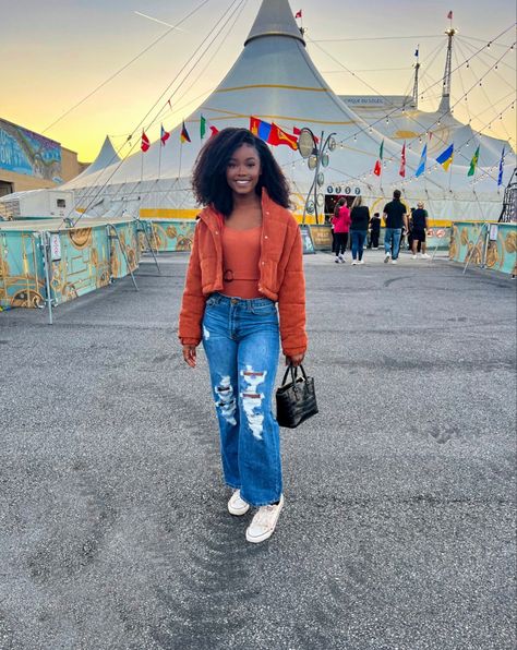 Black woman wearing an amber colored shirt and jacket, standing in front of a circus tent. Circus Date Outfit, Fall Carnival Outfits, Carnival Date Outfit, Orange Halloween Aesthetic, Aesthetic Carnival, Carnival Date, Fall Carnival, Carnival Circus, Date Outfit