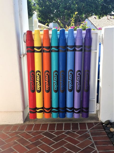 Crayon art. Fence gate made from feed tubes, flower pots, and PVC caps. FASTSIGNS Speedway made the decals. Daycare Gate Ideas, Crayon Fence, Giant Crayon, Art Themed Party, Kindergarten Interior, Daycare Decor, Daycare Design, Diy Classroom Decorations, Whimsical Painted Furniture