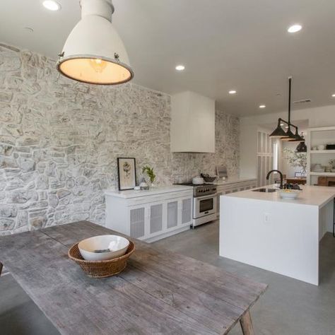 Picture Of a kitchen and dining zone done in modern farmhouse style with a whitewashed stone accent wall that sets the tone and atmosphere here Stone Accent Wall, Gray Floors, County Kitchen, White Kitchen Rustic, Rock The Block, Ford Interior, Stone Accent Walls, House Beautiful Magazine, Natural Stone Wall