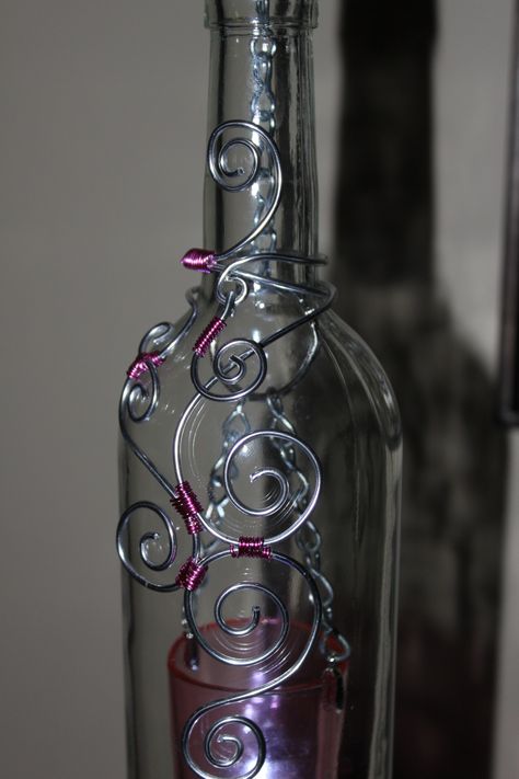 Clear bottle with pink votive, the wire wrap on this one came out really nice, love the simpleness of the pain bottle. Wire Wrapping Bottles, Wire Wrapped Bottles Diy, Wire Wrapped Bottles, Wire Wrap Bottle, Wire Wrapped Glass Bottles, Wire Wrap Glass Bottles, Spiritual Glass Necklace With Wire Wrapped Detail, Silver Wire-wrapped Necklace With Recycled Glass, Wine Bottle Charms