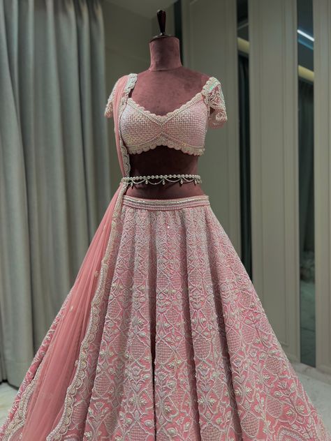 Reverie Bridal set is a stunning coral pink lehenga hand embroidered on pure raw silk fabric with signature glass crystals, pearls, sequins, and beads and has scalloped edges on the lehenga. It's paired with an attractive hand-embroidered blouse with cap sleeves on net fabric. It comes with a peachy pink soft net scalloped dupatta, a gorgeous soft net trail dupatta, and a pearl belt that enhances the entire look.From Rianta's Naayab collection. DELIVERY TIMEPlease allow 8-12 weeks for your outfi Bridal Lehanga Blouses Modern Design, Pink Lehenga For Bride, Mera Aesthetic, Modern Lehangas, Trending Bridal Lehenga, Trending Lehenga Designs, Swiss Vacation, Silk Lengha, Scalloped Dupatta