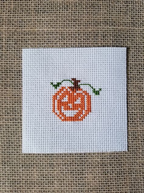 A happy pumpkin finished cross stitch piece.  It was stitched on white aida cloth which measures approximately 3.5" x 3.5".   It's ready to use in a variety of craft projects! Simple Halloween Cross Stitch, Miniature Cross Stitch Patterns Free, Small Halloween Cross Stitch Patterns, Mini Halloween Cross Stitch, Tiny Cross Stitch Patterns Minis, Cross Stitch Sun, Small Christmas Cross Stitch, Cross Stitch Pumpkin, Cross Stitch Fall