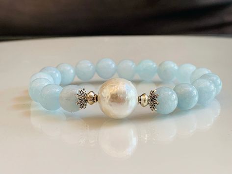 "Bring the ocean to you with this beautiful aquamarine and shell pearl bracelet. These all-natural aquamarine cool blue beads have a soft, almost organic feel to them. At the center is a large 14mm natural shell pearl which makes this bracelet \"Pop\". Choose your aquamarine bead size, available in 10mm or 12mm aquamarine beads. Made with high-quality elastic stretch cord.    BRACELET SIZE INSTRUCTIONS  See 2nd Item Photo for a Pictorial Instruction. We make all our bracelets to actual \"wrist s March Bracelet, Aquamarine Bracelet Beads, Aquamarine Bracelet, Bright Star, Aquamarine Beads, Birthstone Bracelet, March Birthstone, Birthstone Bracelets, Aquamarine Gemstone