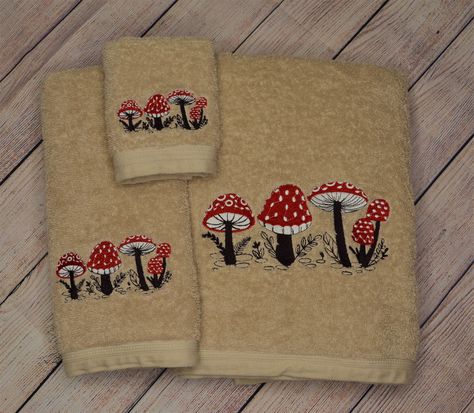 "Embroidered Woodland Mushrooms 3 piece towel set. Deep chocolate brown, ruby red, and snowy white thread make up whimsical mushrooms on tan towels.  Set includes: -1 Bath towel: 27\"x 52\" -1 Hand towel: 16\"x 26\" -1 Wash cloth: 12\"x 12\" All towels are machine embroidered. 100% cotton midweight towels are purchased from JCPenney, Home Expressions brand. Machine wash and dry like normal towels, no bleach." Mushroom Themed Bathroom, Mushroom Bathroom, Tan Towels, Dream Dorm, Fairy Home, Mushroom Decor, Cute Bedroom Decor, Wash Cloth, Cute Home Decor