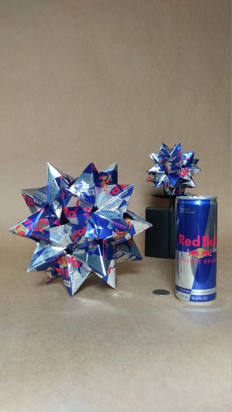 Aluminum Sonobe Kusudama Origami, hand folded from Red Bull Energy Drink cans. Units: 60 Time for Completion: 6-7 hours Assembled in the spirit of traditional paper origami without any glue or fasteners, this metal origami was handfolded from Red Bull cans, not paper. This item is extremely rigid, heavy duty and durable. All sharp edges are folded under, leaving only smooth edges exposed (though handle with care, points are spiky.) Whether you place it on 5 points or 3 points, the symmetry is be Crafts With Aluminum Cans, Things To Make Out Of Soda Cans, How To Make Bottle Cap Art, Drink Can Crafts, Red Bull Can Crafts, Redbull Can Diy, Can Sculpture Ideas, Recycled Soda Cans, Soda Can Art Sculptures