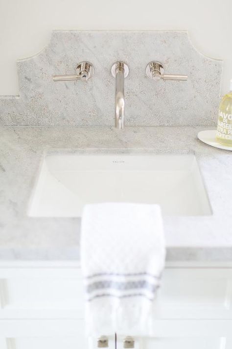 A polished nickel faucet is mounted to a curved marble backsplash above a Kallista sink fixed to a gray marble countertop complementing a white bath vanity. Marble Backsplash Bathroom, Polished Nickel Faucet, Wall Faucet, Bathroom Lamp, Wall Mount Faucet Bathroom, Brick Backsplash, Stone Backsplash, Transitional Bathroom, Marble Backsplash