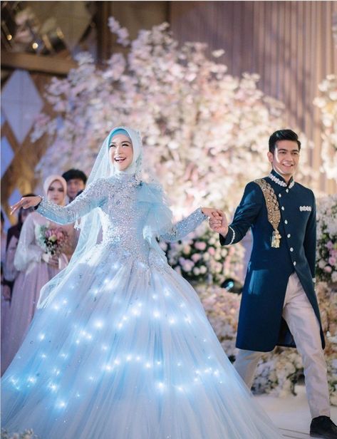 Ria Ricis tampil bak putri raja mengenakan ballgown yang dapat menyala. Gaya serupa juga pernah dipakai Rachel Vennya saat menikah dengan Niko Al Hakim. Rachel Vennya, Engagement Dress For Groom, Upacara Adat, Wedding Dress Hijab, Muslim Wedding Gown, Blue Wedding Gowns, Nikah Outfit, Dresses Hijab, Muslimah Wedding Dress