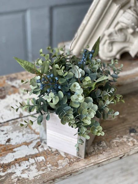 A bountiful collection that will certainly warrant second glances! Cool eucalyptus serves as a backdrop for arcing leaves and shoots of blue berries. Centerpiece is housed in a wooden box with metal details at edges.9" x 9" x 10" (box measures 4.75” x 4.75” x 4.75”) Potted Plant Centerpieces, Navy Centerpieces, Eucalyptus Wedding Centerpiece, Lantern Wall Decor, Green Wedding Centerpieces, Eucalyptus Centerpiece, Plant Centerpieces, Road Trip Gifts, Blue Berries