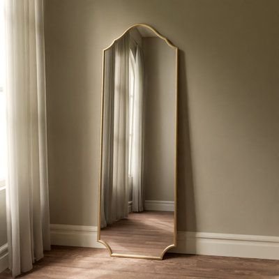 Dark with a bit of flair. This free standing, full length metal mirror provides a modern gothic aesthetic to your home! Perfect for bedrooms, dressing areas, and entryways - This tall beauty catches your body from head to toe so you can see your whole outfit with ease. Featuring an iron frame finished in a matte black to provide a timeless splash of dark style to any room its placed in! The dark finish encourages this mirror to blend in your home, while the touch of flair in the styling adds to Tall Gold Mirror In Bedroom, Floor Mirror Gold, Long Gold Mirror, Mirror Stand Decor, Living Room Full Length Mirror, Mirrors Bedroom, Big Wall Mirror, Gold Full Length Mirror, Vintage Standing Mirror