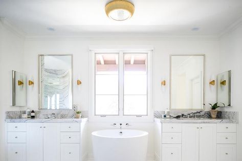 Oval freestanding bathtub between his and her washstands topped with gray marble countertops showcasing polished nickel mirrors. Tub Between Two Vanities, Stunning Showers, Gray Marble Countertops, Aesthetic Bathroom Decor, 20 Aesthetic, Japanese Soaking Tubs, Zen Bathroom, Aesthetic Bathroom, Transitional Bathroom