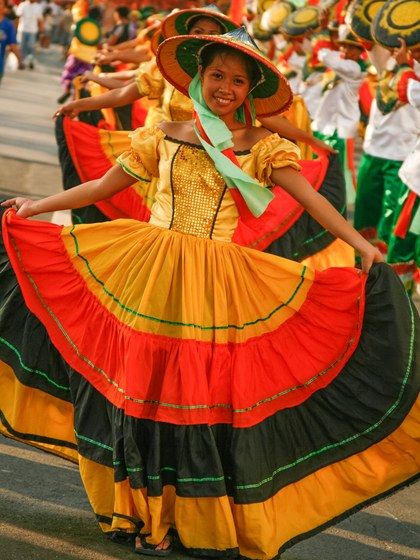 Philippine native dances and attire have over generations incorporated European, Latin American, and Asian influences. This Manileño festival costume bears a striking resemblance to the native dress of Andalusia, but bears Mexican-inspired colors and is topped by a traditional Filipino salakot hat. Columbian Traditional Clothing, Festival Dance Philippines, Folk Dance Costume Philippines, Sinulog Festival Costume, Festival Costumes In The Philippines, Learning Tagalog, Philippine Traditions, Philippine Festivals, Vintage Filipino