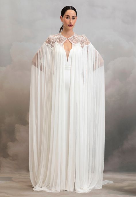 Add instant glamour to your bridal look with the dramatic Aster Cape. Pearl scalloped tulle embrace the neckline and shoulders of this whimsical cape before it drapes down in the softest 100% silk tulle. We suggest pairing this piece with a classic wedding gown or a topper and silky bridal trouser set to instantly elev Pearl Cape, Classic Wedding Gown, Wedding Cloak, Catherine Deane, Fantasy Outfits, Lace Cape, Cape Wedding Dress, Cape Gown, Fairytale Fashion