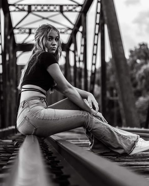 Black and white. Railroad bridge. Jeans and a black half shirt. Blonde girl sitting on railroad bridge. Photoshoot Railroad Tracks, Poses On Railroad Tracks, Photoshoot On Railway Track, Senior Pics On Train Tracks, Senior Picture Ideas On Railroad Tracks, Female Senior Picture Poses Photo Ideas, Railroad Track Photoshoot Senior Pics, Cute Senior Photoshoot Ideas, Senior Pictures Women