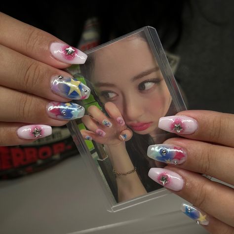 A picture of colorful nails with stars and chrome charms, holding a photocard of Le Sserafim's HUH YUNJIN with the same nails. Huh Yunjin Nails, Yunjin Lesserafim Nails, Lesserafim Nails Inspired, Le Sserafim Nails Inspired, New Jeans Inspired Nails, Le Sserafim Nails Designs, Newjeans Inspired Nails, Le Sserafim Tattoo, Kpop Inspo Nails