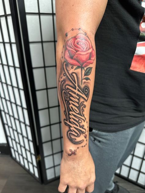 Name with rose and rosary Name With Rosary Tattoo, Name Tattoos With Rose, Tattoo With Siblings Names, Name With Roses Tattoo, Rose Rosary Tattoo, Mom Name Tattoo For Men, Moms Name Tattoo Ideas Men, Name With Rose Tattoo, Rose And Name Tattoo