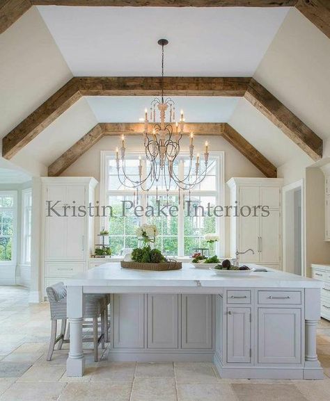 Elegant kitchen with vaulted ceilings lined with rustic wood beams accented with a French candle chandelier illuminating an oversized French grey island topped with white marble. Vaulted Ceiling Decor, Vaulted Ceiling Ideas, Vaulted Ceiling Lighting, Vaulted Ceiling Kitchen, Vaulted Ceiling Living Room, Ceiling Kitchen, Faux Beams, Wood Beam Ceiling, Kitchen Ceiling