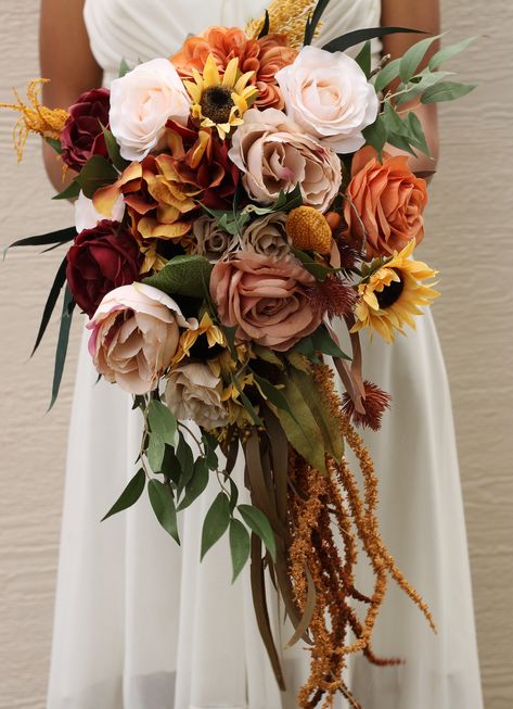 Beautiful fall inspired bouquet that has a exquisite design and details which would make a wonderful accessory for your special day. Lush roses in burnt orange, mustard, brown, blue and burgundy hues along with a array of artificial greenery and preserved accents.  Available with ribbon or twine wrapped base.  You have the option to wrap the base of the bouquet with twine, ribbon or both the choice is yours. :) If you would like any alterations or custom requests we would love to hear your ideas Boho Cascade Bouquet, Bridal Bouquet With Sunflowers, Beige Wedding Bouquet, Burnt Orange Bridal Bouquet, Burgundy Sunflower, Burnt Orange Flowers, Tiny Bouquet, Fall Bridal Bouquet, Church Sanctuary