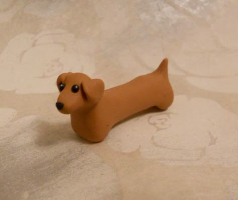 Doxie Desserts: This dachshund is handmade with FIMO and sold by GraceAndFlowers on Etsy. This simple shape could easily be recreated with fondant for use as a cake topper. Clay Sausage Dog, Weiner Dog Clay, Polymer Clay Sausage Dog, How To Make A Clay Dog Easy, Clay Weiner Dog, How To Make A Dog Out Of Clay, Dachshund Clay Sculpture, Polymer Clay Dachshund, Cute Clay Dog