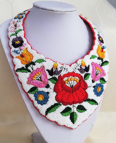 Kalocsa style beadembroidery neckpiece The art of Kalocsa embroidery was born in the second half of the 19th century at southern part of Hungary. Originally the needlework was only white and the embroidery patterns were merely made up by holes. The women at Kalocsa an its area embroidered ready-to-make patterns, but few gifted artists started to design their own design. The compositions were very simple and clearly arranged.  In the 19th century the art of Kalocsa embroidery went through creative innovations. The holes of the pattern designs were filled but there were also many artists who liked to combine the two needlework styles. At the beginning of the 20th century the treasury of flower motifs kept growing, and coloured emboideries appeared, too, which tendecy was supported by the  op Athabascan Beadwork, Kalocsa Embroidery, Folk Motif, Hungarian Embroidery, Embroidered Necklace, Flower Motifs, Bunch Of Flowers, Handmade Jewellery, Pansies