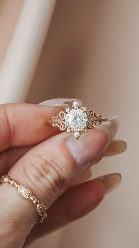 A vintage-style engagement ring with a round center stone, surrounded by small diamonds and delicate decorative patterns on the band. Vintage Gold Engagement Rings Victorian, Victorian Wedding Ring Antique Jewelry, Vintage Gold Rings Antiques, Timeless Wedding Rings Vintage, Vintage Wedding Rings 1920s Antique, Wedding Rings Engagement Oval, Engagement Ring With Pearls, Engagement Rings Victorian, Engagement Rings Pearl