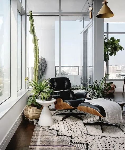 a chic nook with a black lounger and ottoman, a printed rug, potted greenery around is a very cozy space to read here Eames Chair Living Room, Black Eames Chair, White Scandinavian Living Room, Michael Hsu, Black Lounge Chair, Small Sunroom, Taupe Walls, Lounge Chairs Living Room, Ball Chair