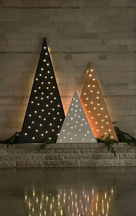 Drilled holes in stained triangular-cut plywood and pushed stringed light bulbs into each one. Wood Christmas Tree With Lights, Plywood Christmas Tree, Plywood Christmas, Christmas Stage Design, Pallet Wood Christmas, Christmas Session, Christmas Party Backdrop, Wood Trees, Selling Ideas