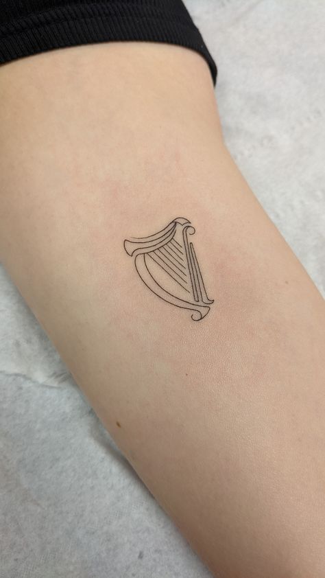 Fineline delicate Irish harp tattoo Ireland Harp Tattoo, Simple Harp Tattoo, Harp Tattoo Minimalist, Harp Tattoo Small, Guiness Tattoos Small, Irish Harp Tattoos For Women, Irish Dance Tattoo, Irish Symbols Tattoos, Small Ireland Tattoo