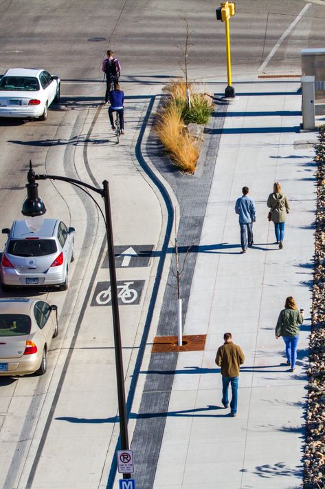 thoughtfully integrates the corridor's railroad history by reclaiming and utilizing granite curbstones. The design creatively accommodates safety through the use of an elevated and protected lane, providing curb extensions and enhanced crosswalk markings for pedestrians, and utilizing curb extended boarding areas for transit users. with stormwater connected planting beds and an enhanced overall streetscape appearance. Street Parking Design, Traffic Calming Urban Design, Pedestrian Street Design, Bike Lane Design, Crosswalk Design, Streetscape Architecture, Pedestrian Lane, Streetscape Design, Pedestrian Walk