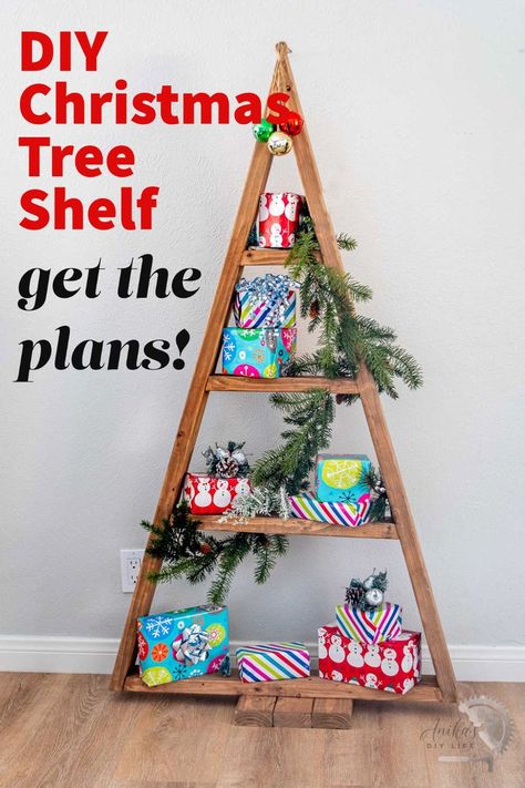 DIY wooden Christmas tree shelf with presents and faux greenery. with text overlay Wood Christmas Tree With Shelves, Diy Christmas Tree Shelf For Village, Tree Shelf For Christmas Village, Wooden Christmas Trees Shelves, Wood Christmas Tree Shelfs, Tree Shelf, Wooden Christmas Tree Decorations, Christmas Diy Wood, Alternative Christmas Tree