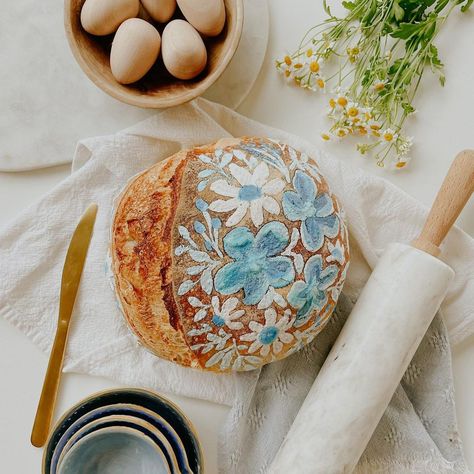 Loveall Design Co.™ on Instagram: “This blue floral loaf needed a permanent spotlight on the feed 🫶🏼 . . . #sourdough #paintedsourdough #floraldesign #sourdoughbread” Decorative Sourdough Bread, Painting On Sourdough, Sourdough Bread Art, Painting On Sourdough Bread, Painted Bread Loaf, How To Paint Sourdough Bread, Sourdough Painting, Painted Sourdough Bread, Sourdough Bread Designs