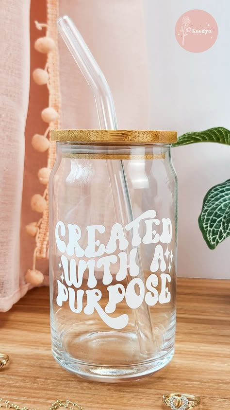 With its unique vinyl design featuring the quote "Created With A Purpose", it is sure to add that extra touch to your morning routine, hanging out with friends, or going about your daily tasks. The included bamboo lid and glass straw allow this glass to be eye-catching yet functional. Tumblers With Quotes, Christian Glass Cups, Aesthetic Soda Can, Glass Cups With Vinyl Cute Ideas, Glass Cup Design Ideas, Tumbler Ideas Vinyl, Cups With Vinyl Cute Ideas, Purpose Aesthetic, Aesthetic Soda