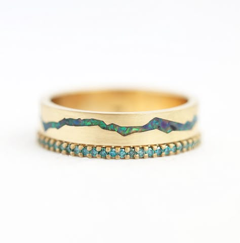 Rowan Lab Opal Band with Teal Diamonds This one-of-a-kind wedding band which represents mountain range made out of crushed peacock opal and round teal diamonds is truly something that every nature and mountain lover should have. READY TO SHIP in 14k yellow gold and US 8. See our Rowan ring with black spinel and black diamonds here. Details   Main gemstone: Lab black (peacock) opal inlay  Side gemstones: Teal diamonds  Shape: Round  Cut: Full cut  Measurements: 1.10mm (56)  Band width: approx. 5. Opal Inlay Ring, Wedding Rings Design, Opal Band Ring, Opal Wedding Band, Opal Band, Flawless Diamond, Mountain Lover, Blue Diamonds, Diamonds Ring