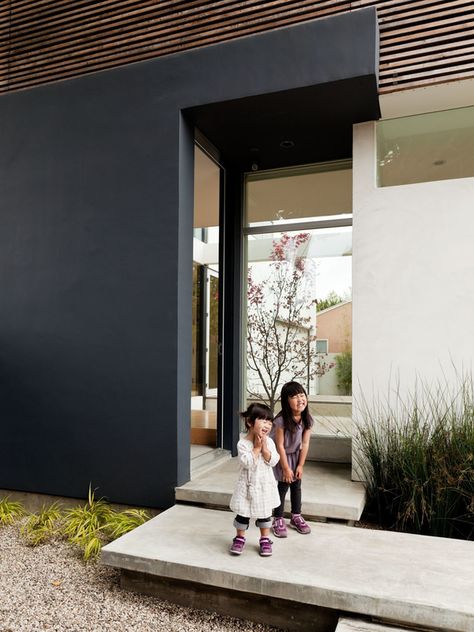 Yumi (left) and Maya (right) cheese around on the steps leading into the front door. Inside, there is ample space for removing and leaving one's shoes, another Japanese element. Modern Japanese House, A Modern House, Dwell Magazine, Concrete Steps, Dark Wall, Los Angeles Homes, Concrete Patio, Japanese House, Wood Slats