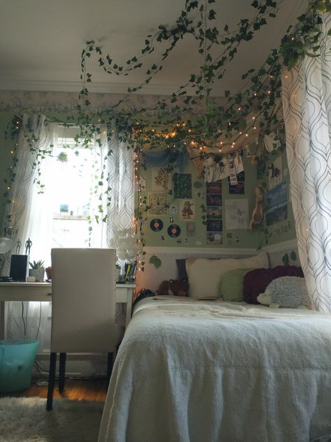 Enchanted forest bedroom inspo, vines, fairy lights, posters, pillows, cottagecore bedroom idea, cute interior, green, overgrown, warm Vines On Roof Bedroom, Green Cottagecore Bedroom, Overgrown Bedroom, Forest Green Bedroom Ideas, Overgrown Bedroom Aesthetic, Fake Vine Bed Canopy, Ivy Bed Canopy, Room With Tapestry And Vines, Room Ideas Aesthetic Tapestry And Vines