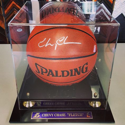 In addition to custom framing, we can also provide custom display cases and name plates for your memorabilia! This basketball signed by Chevy Chase, is protected with a UV filtered case with a custom name plate! #denver #colorado #chevychase #fletch #displaycases #lakers Basketball Shadow Box Ideas, Basketball Card Display, Softball Display Case, Framed Basketball Jersey, Jersey Display Case, Custom Display Case, Basketball Signs, Framed Jersey, Chevy Chase