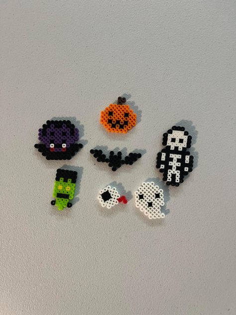 These are keychain sized Halloween designs made of Perler beads. Melt Beads Patterns Halloween, Halloween Perler Beads 3d, Melty Bead Halloween, What To Do With Perler Bead Creations, Perler Bead Pants Chain, Halloween Perler Bead Patterns Pumpkins, Music Note Perler Beads, Perler Beads Cats, Mini Perler Bead Patterns Halloween