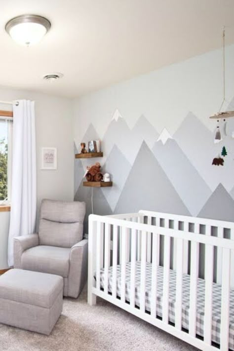 The Baby nursery has a gray mountain mural behind a crib and chair. Baby Boy Nursery Room Design, Mountain Nursery Theme, Boy Nursery Themes, Baby Nursery Inspiration, Mountain Nursery, Baby Room Neutral, Baby Room Themes, Baby Nursery Neutral, Nursery Room Design